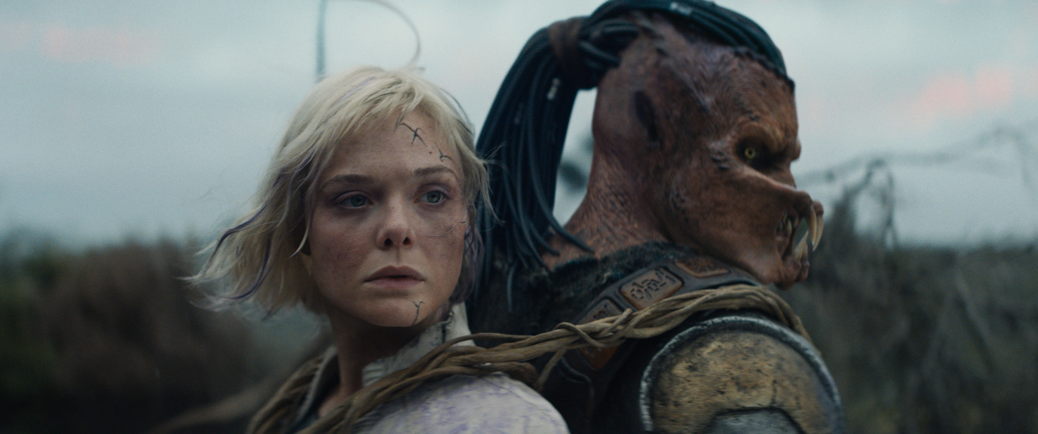 (L-R) Thia (Elle Fanning) and Dek (Dimitrius Schuster-Koloamatangi) in 20th Century Studios' PREDATOR: BADLANDS film. Photo courtesy of 20th Century Studios. © 2025 20th Century Studios. All Rights Reserved.