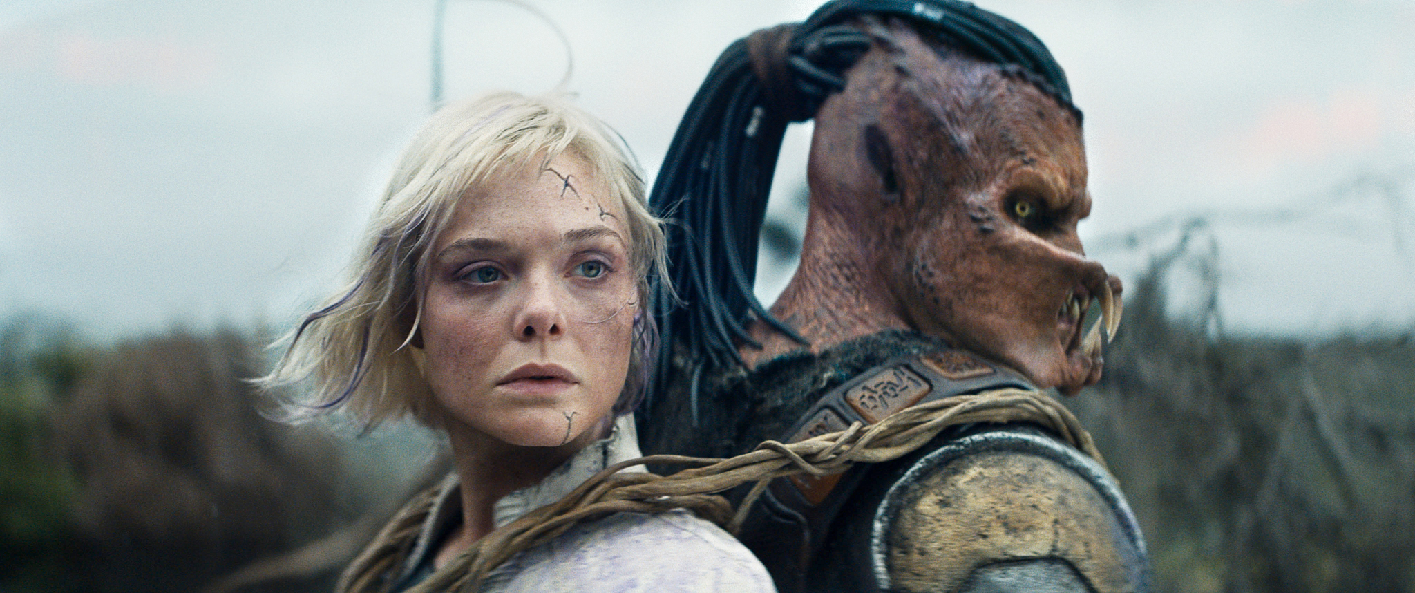 (L-R) Thia (Elle Fanning) and Dek (Dimitrius Schuster-Koloamatangi) in 20th Century Studios' PREDATOR: BADLANDS film. Photo courtesy of 20th Century Studios. © 2025 20th Century Studios. All Rights Reserved.