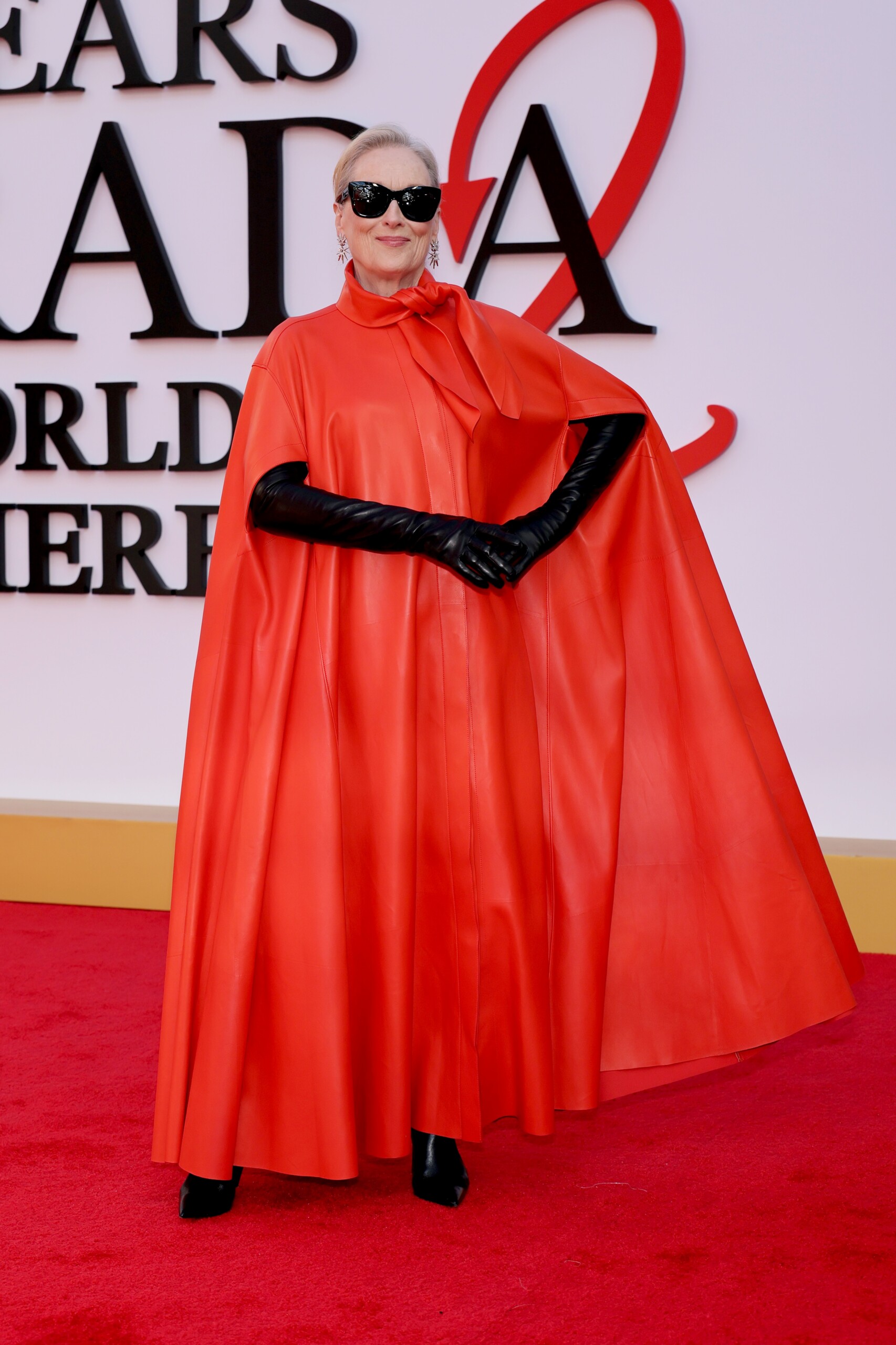Meryl Streep indossa una mantella in pelle rossa con fiocco e occhiali